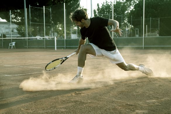 Tennisspieler rutscht auf Sandplatz und spielt Rückhand